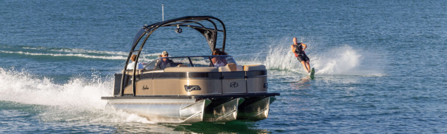 A person waterskiing off an Avalon® Catalina pontoon boat in a body of water.